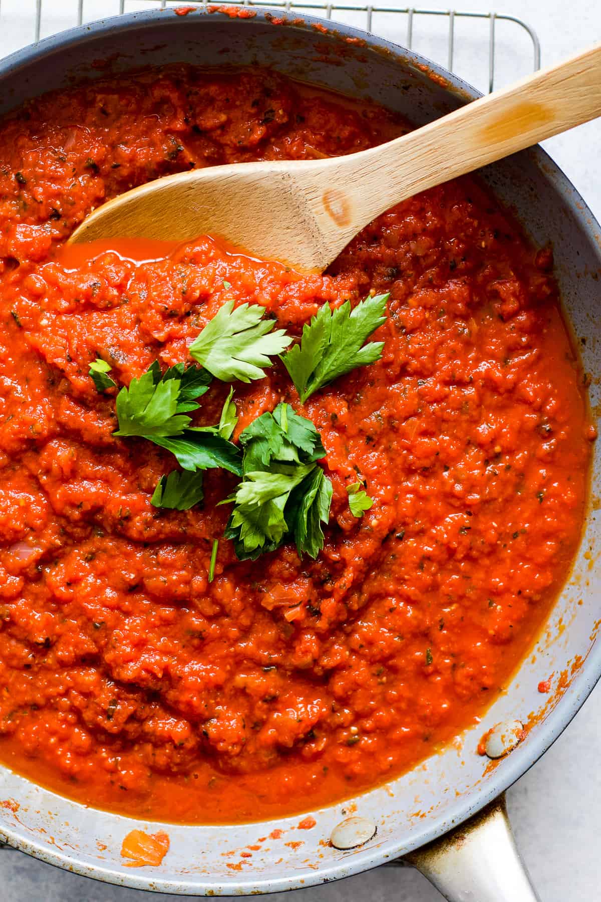 Homemade marinara sauce in gray pan with a few pieces of fresh parsley sprinkled on top.