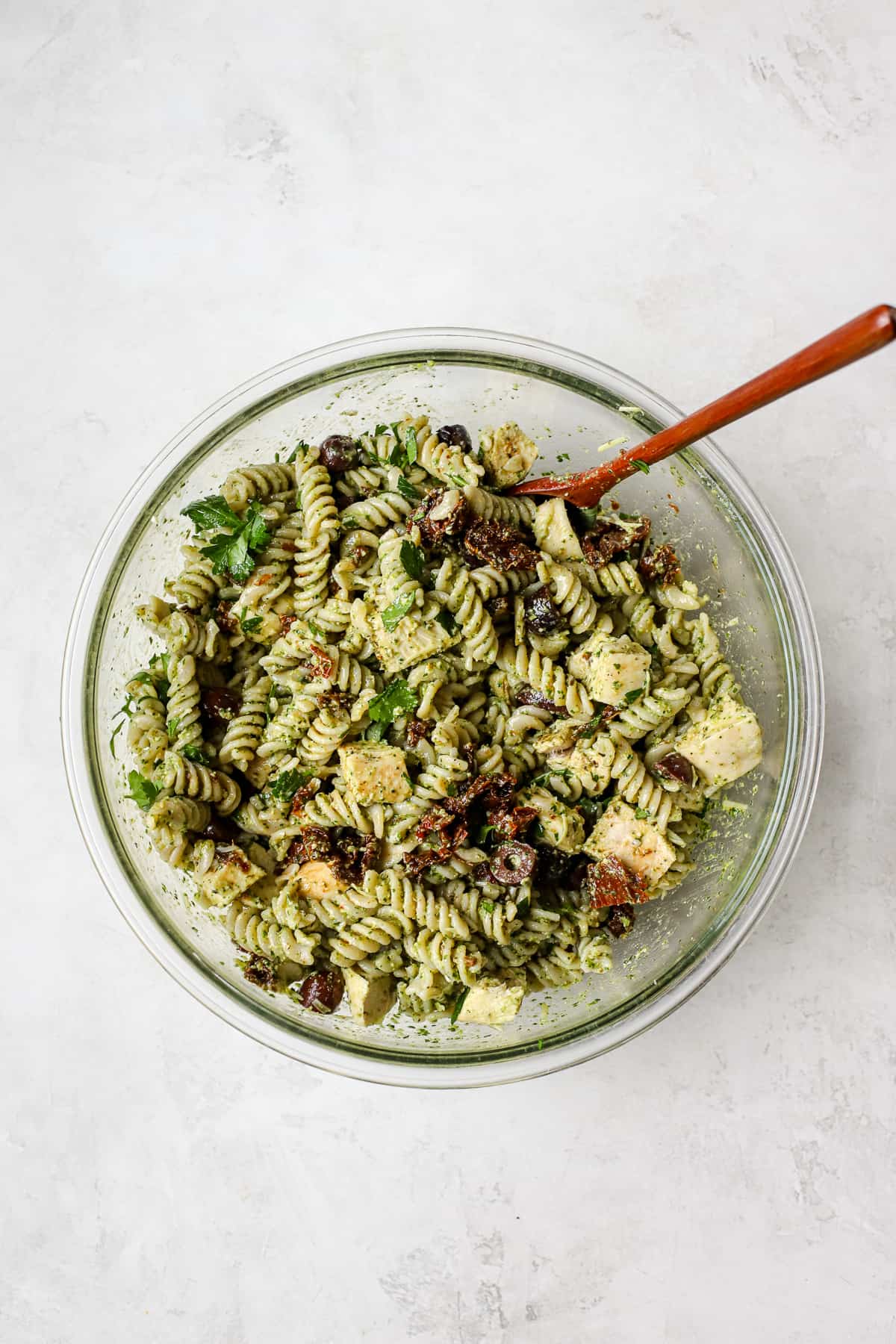 Pesto pasta salad with chicken in a large bowl.