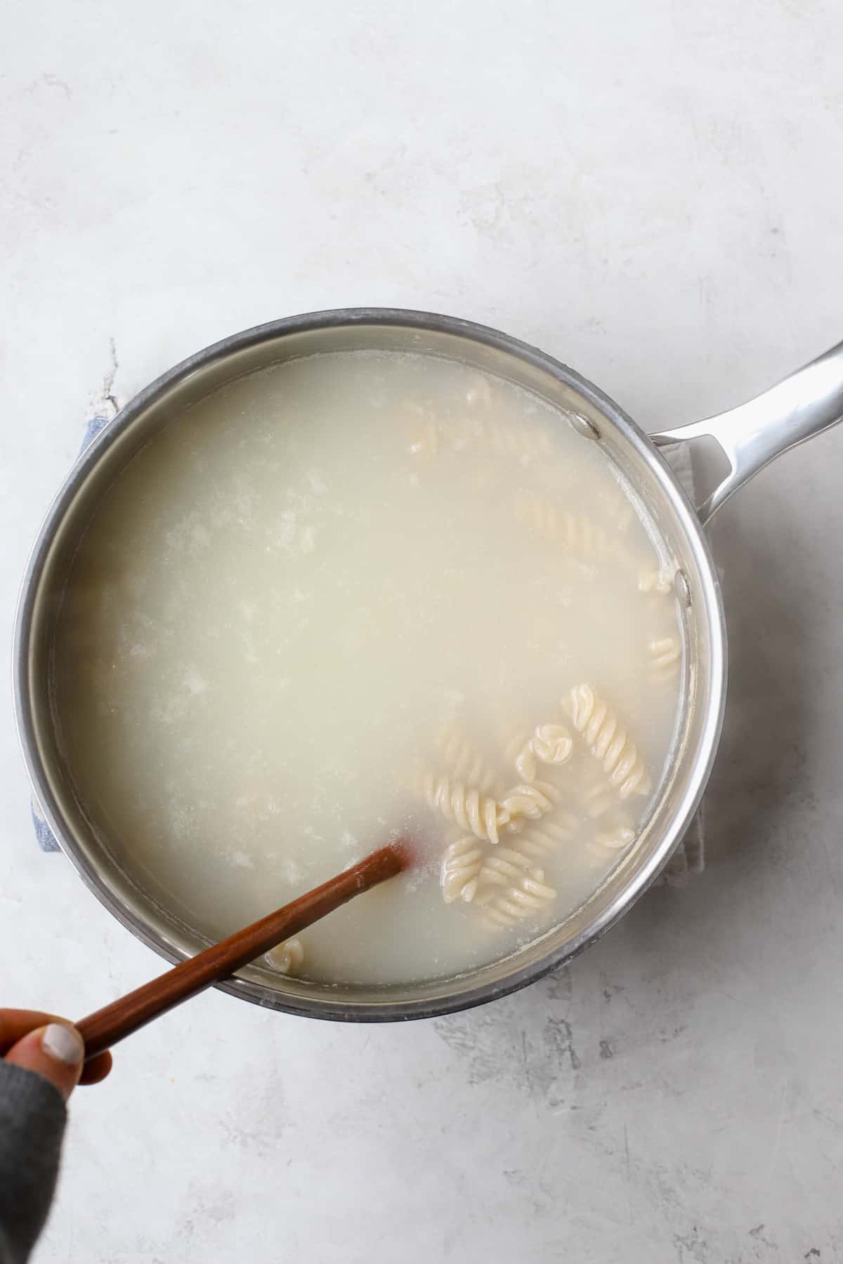 Rotini being cooked in a stainless steel pot.