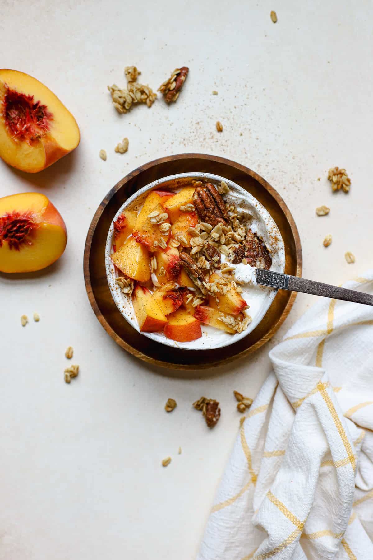 Fresh peach pie yogurt bowl in small white bowl with spoon.