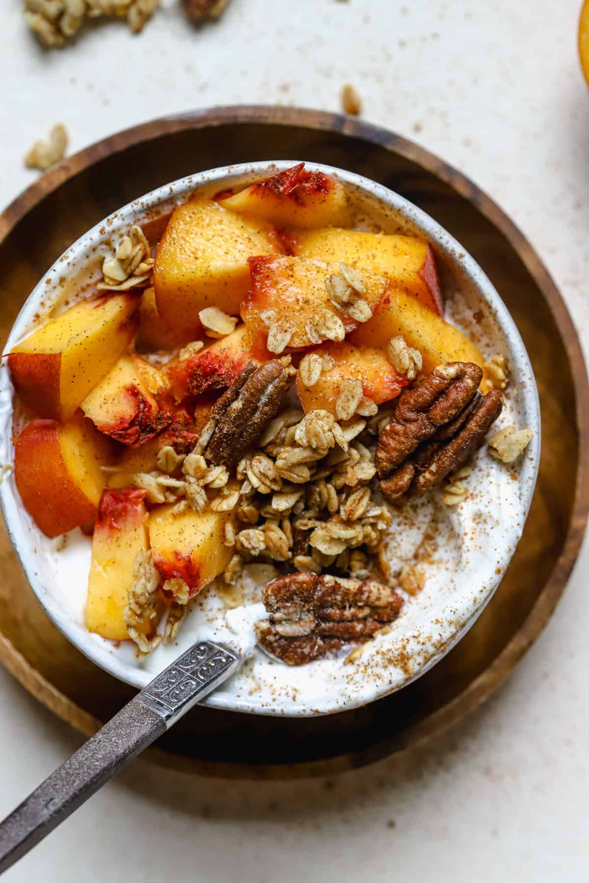 Fresh peach pie yogurt bowl in small white bowl with spoon.