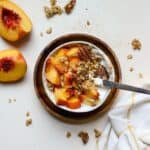 Fresh peach pie yogurt bowl in small white bowl with spoon.