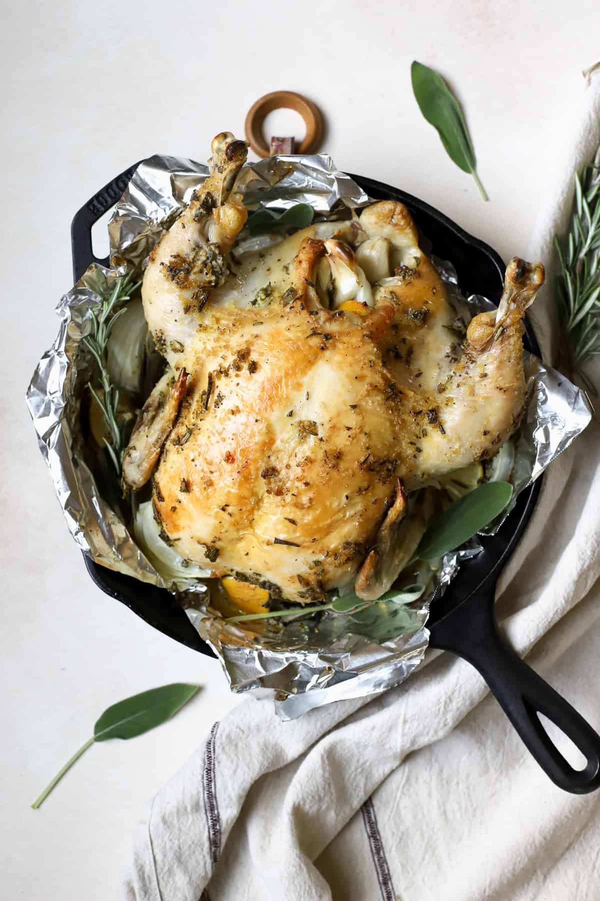 Simple whole roasted chicken with herbs in cast iron skillet.