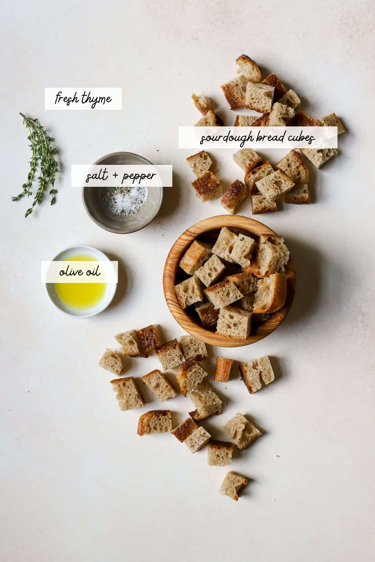 Ingredients needed for sourdough croutons, including sourdough bread, olive oil, and seasonings.