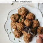 Fork spearing one meatball from a plateful of turkey meatballs.