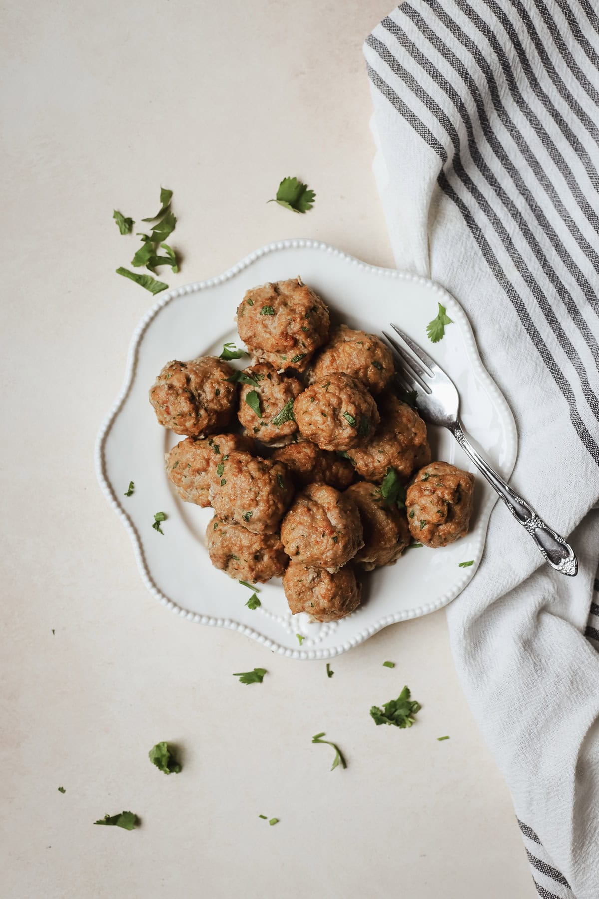 Baked turkey meatballs piled onto a white plate with fork.