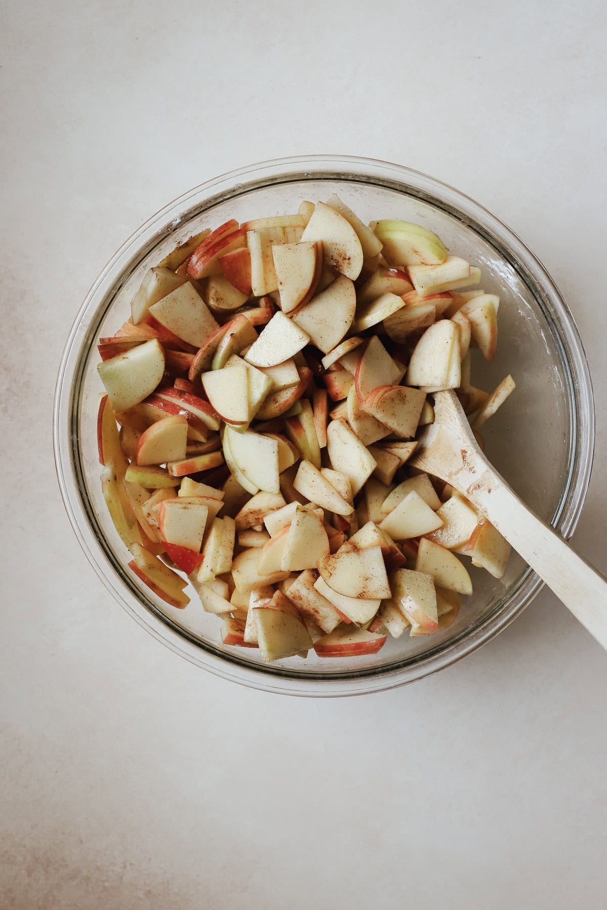 Thinly sliced apples in large bowl with apple crisp filling ingredients.
