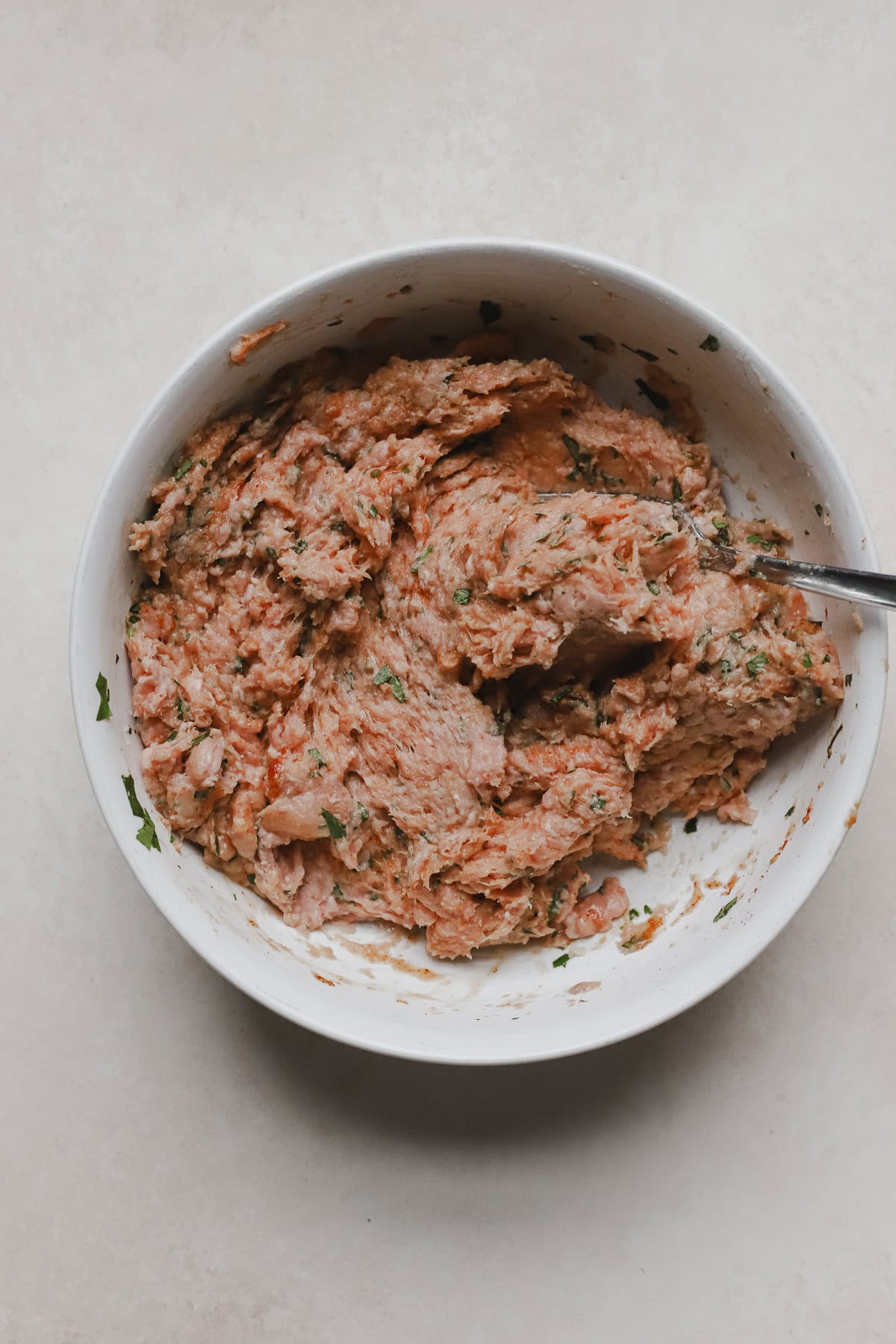 Thoroughly mixed turkey meatballs ingredients in white bowl.