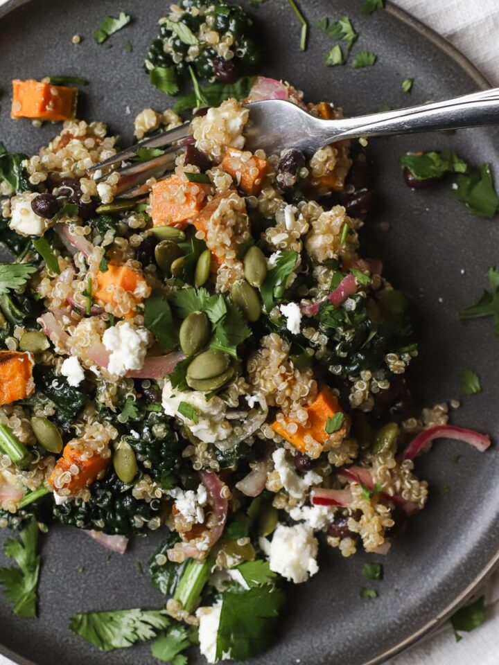 Black bean quinoa salad with sweet potatoes on gray plate with fork scooping up a bite.