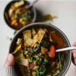 Chicken tortilla soup in gray bowl with spoon.