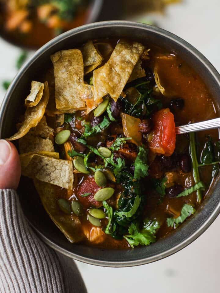 Chicken tortilla soup in gray bowl with spoon.