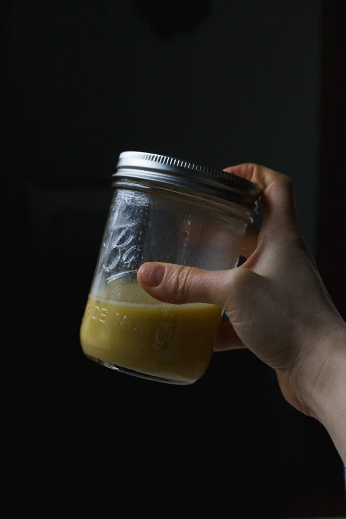 Citrus vinaigrette being shaken together in jar.