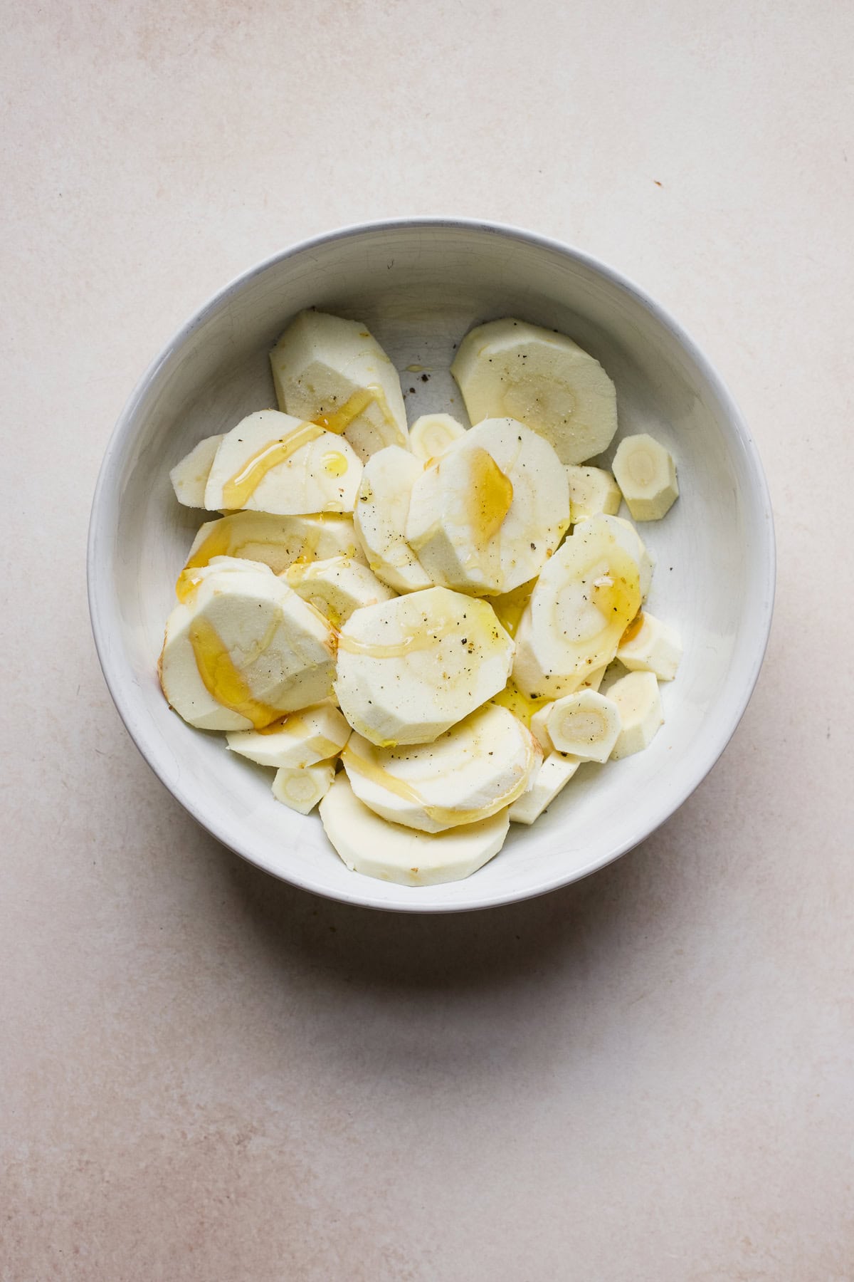 Parsnip slices seasoned with olive oil, honey, salt, and pepper.