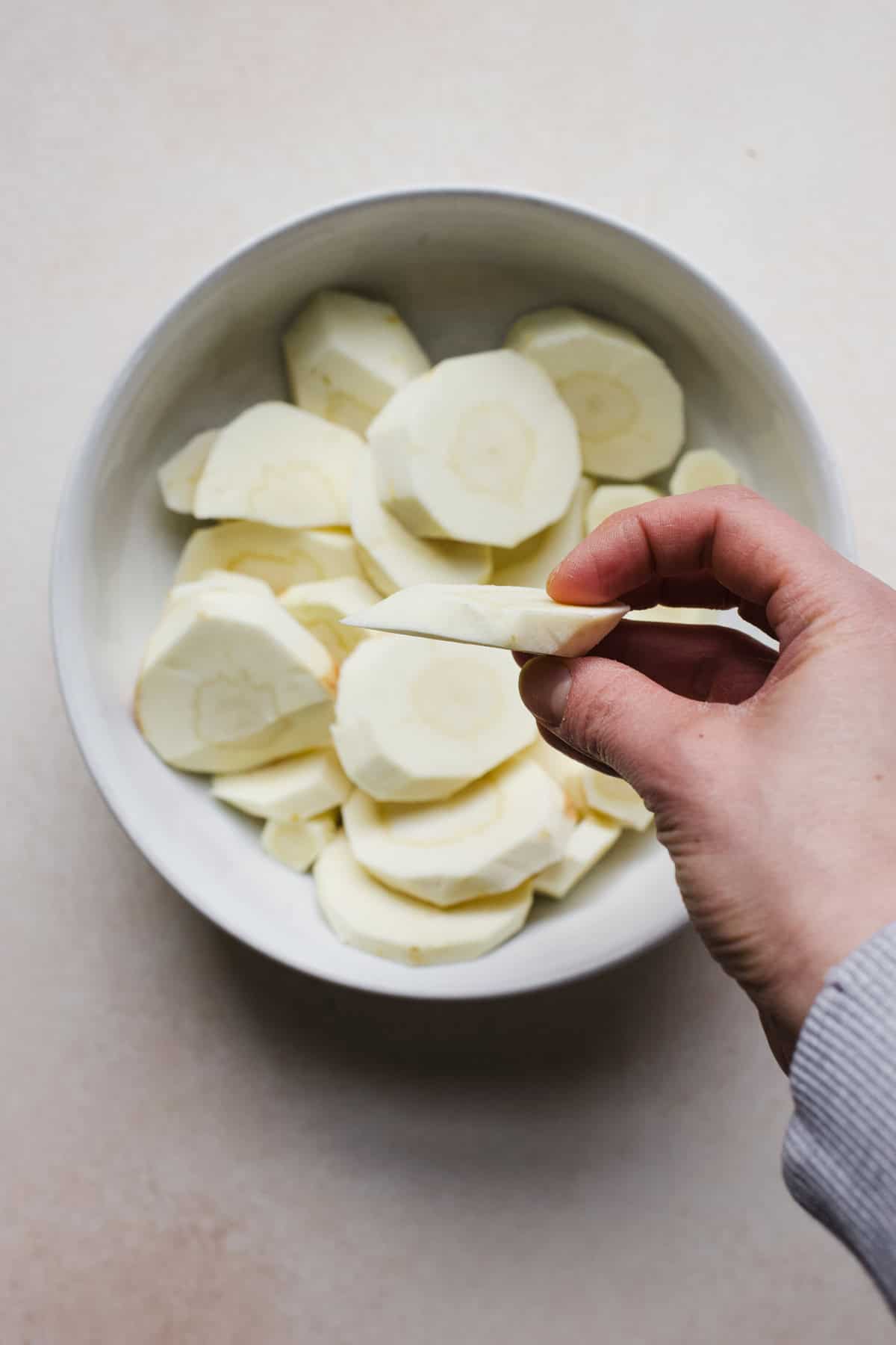 Hand holding a sliced parsnip.