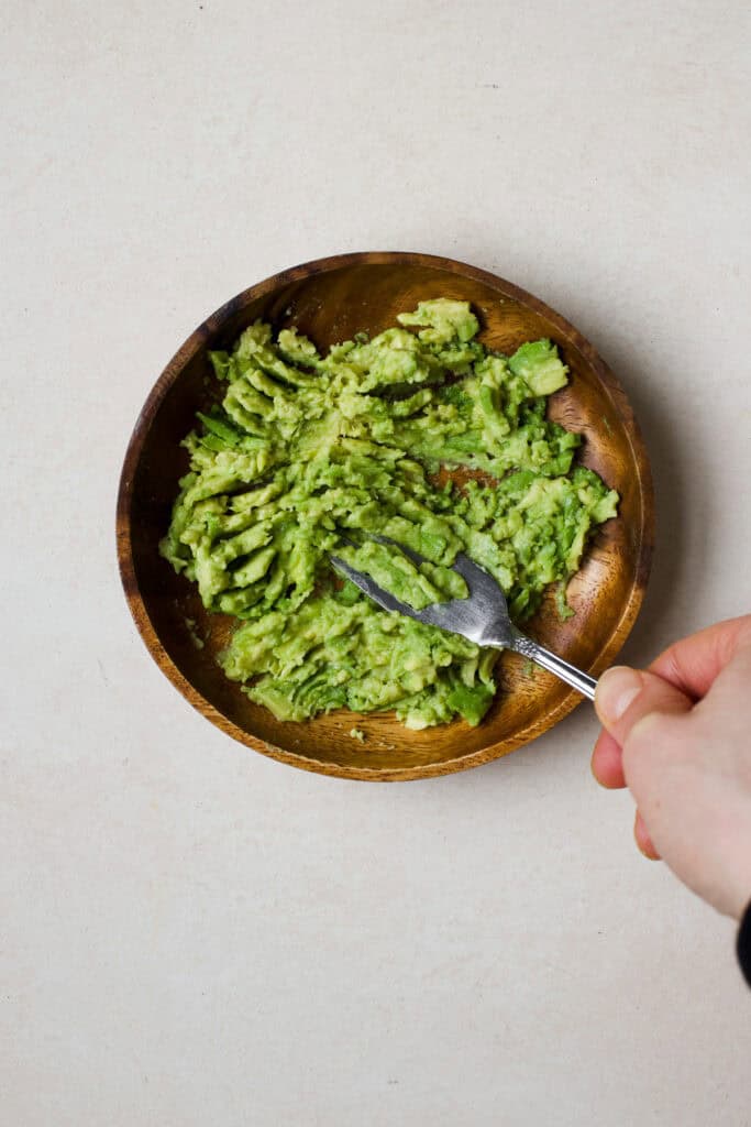 Avocado being mashed with a fork.