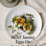 Jammy egg on avocado toast on a plate with matcha on the side.