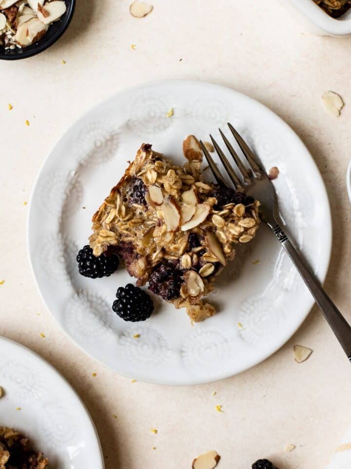 Slice of blackberry baked oatmeal on small plate with fork.