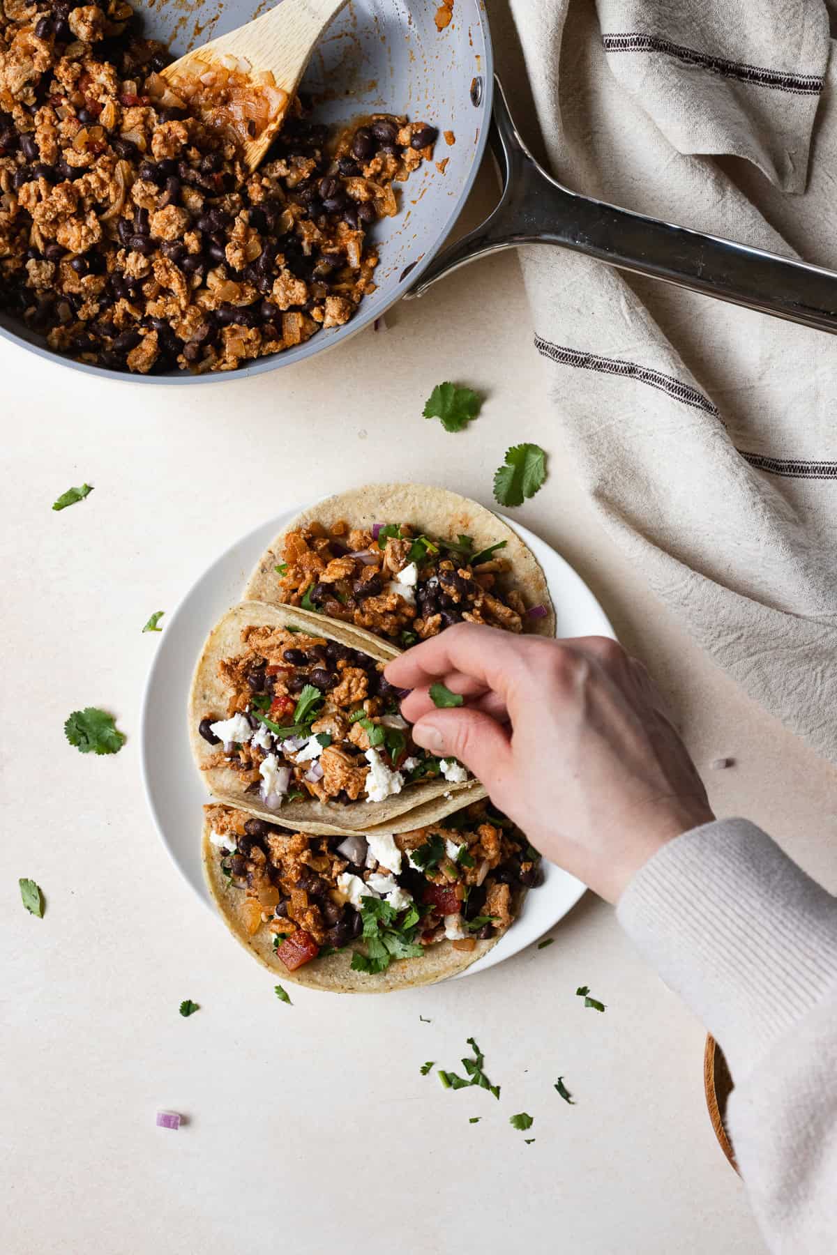 Sprinkling cilantro onto tacos.
