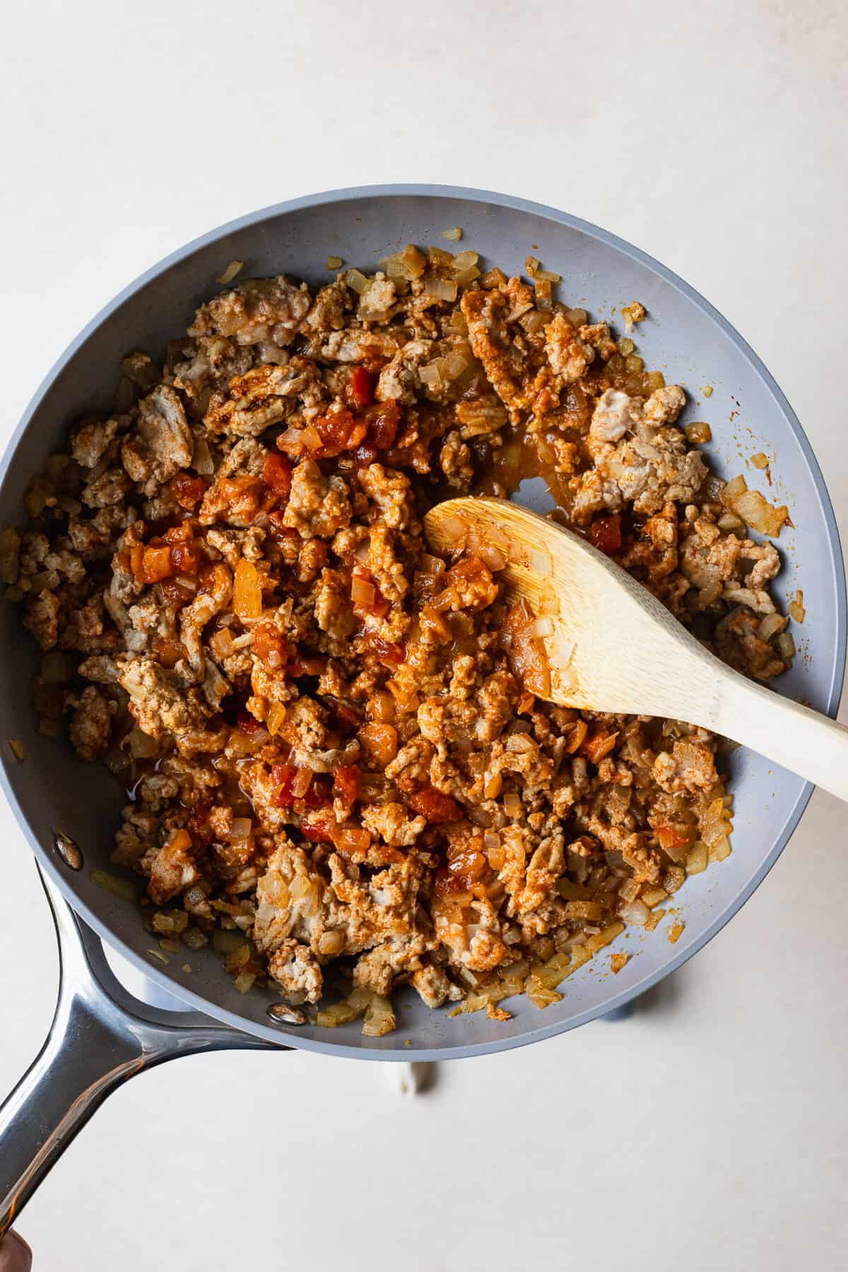 Stirring salsa and taco seasoning into ground chicken.