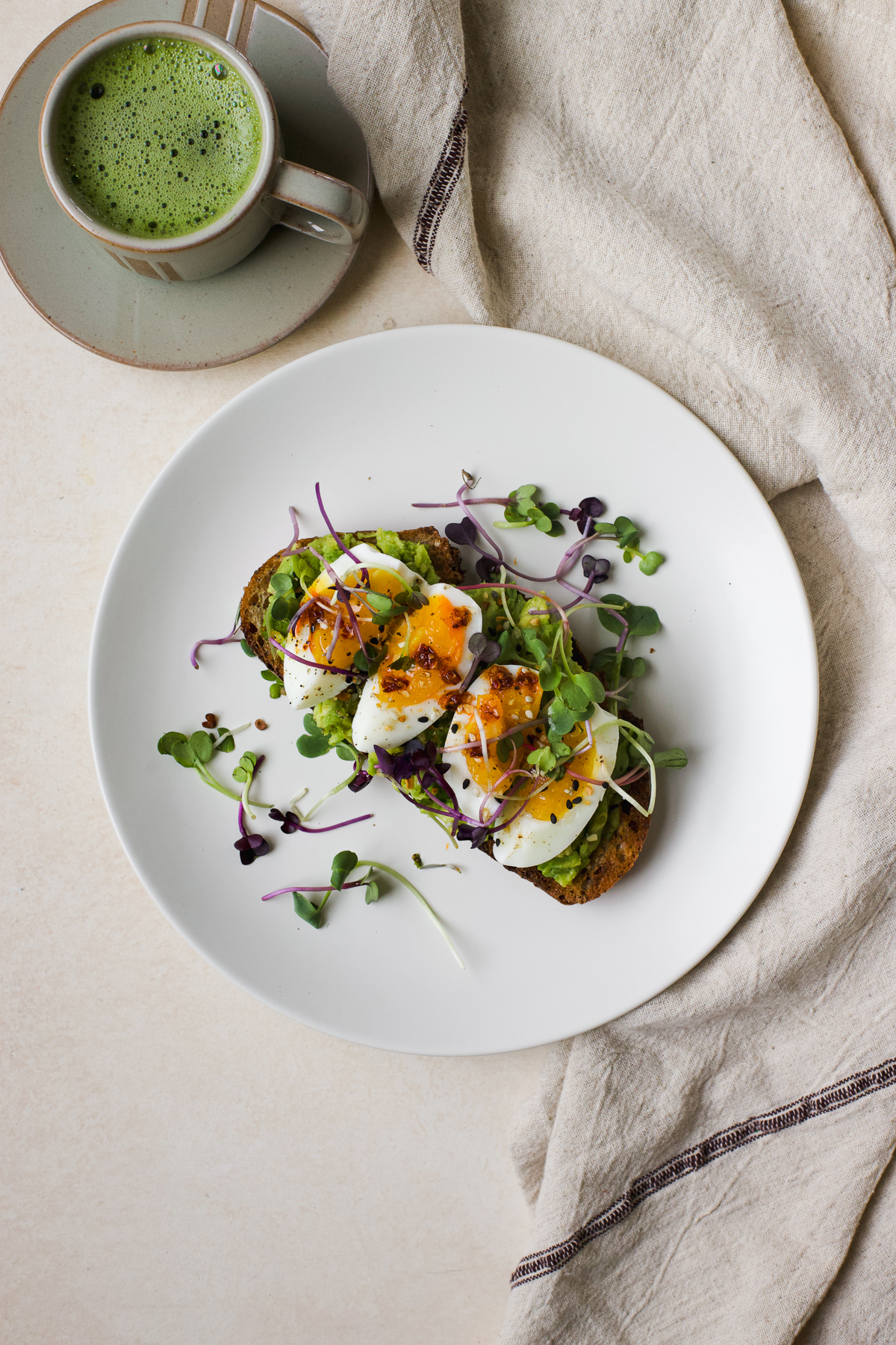 Jammy egg on avocado toast on a plate.