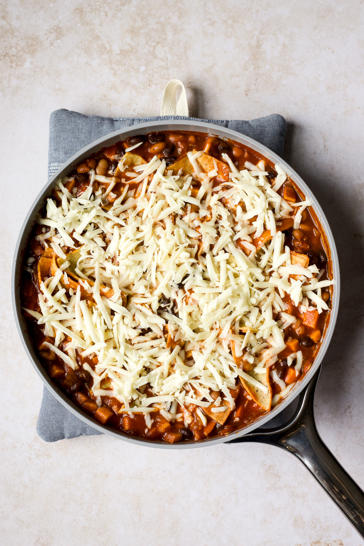 Topping veggie and bean enchilada skillet with Jack cheese.