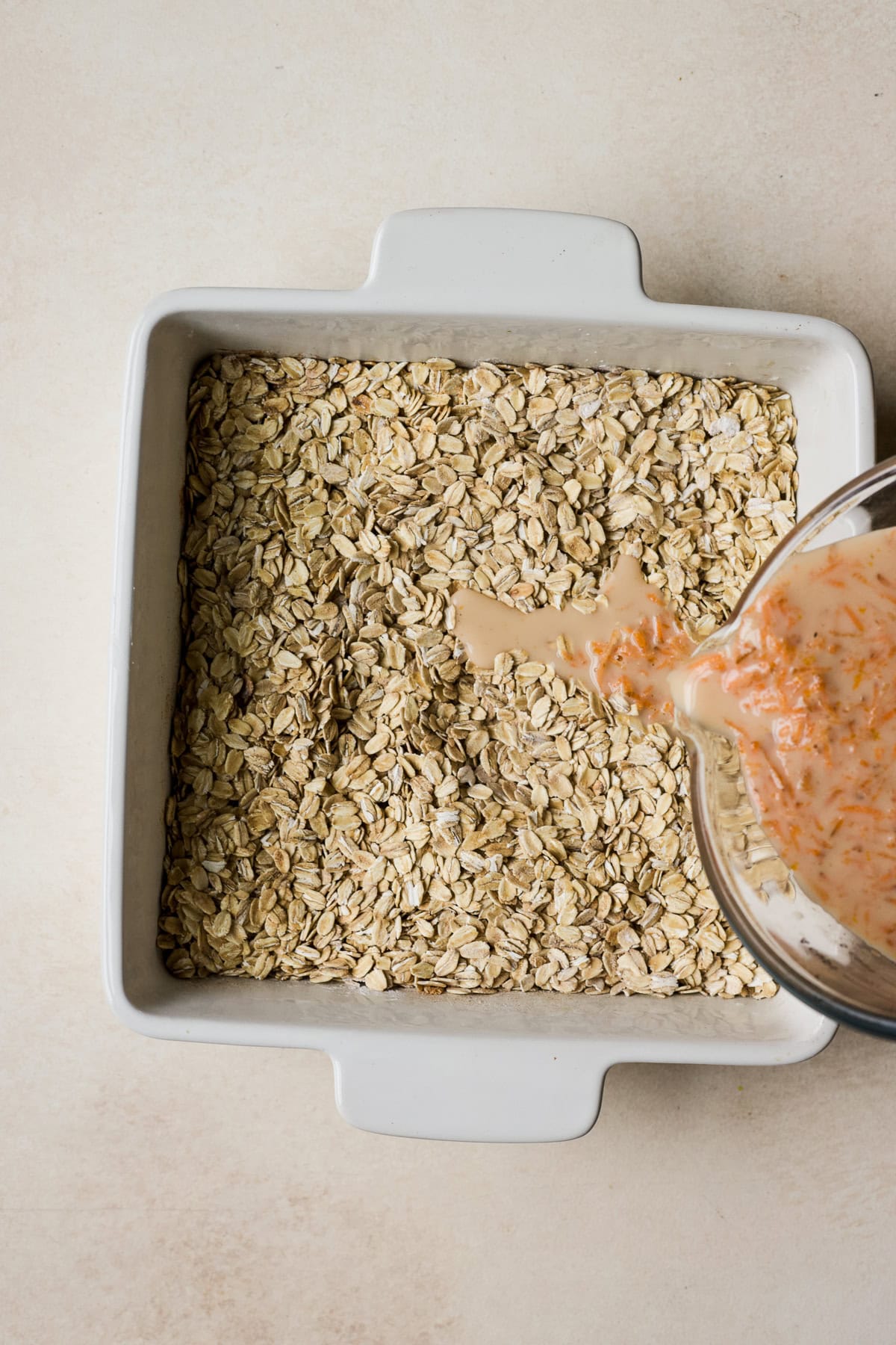 Pouring wet ingredients into baking dish with oats.