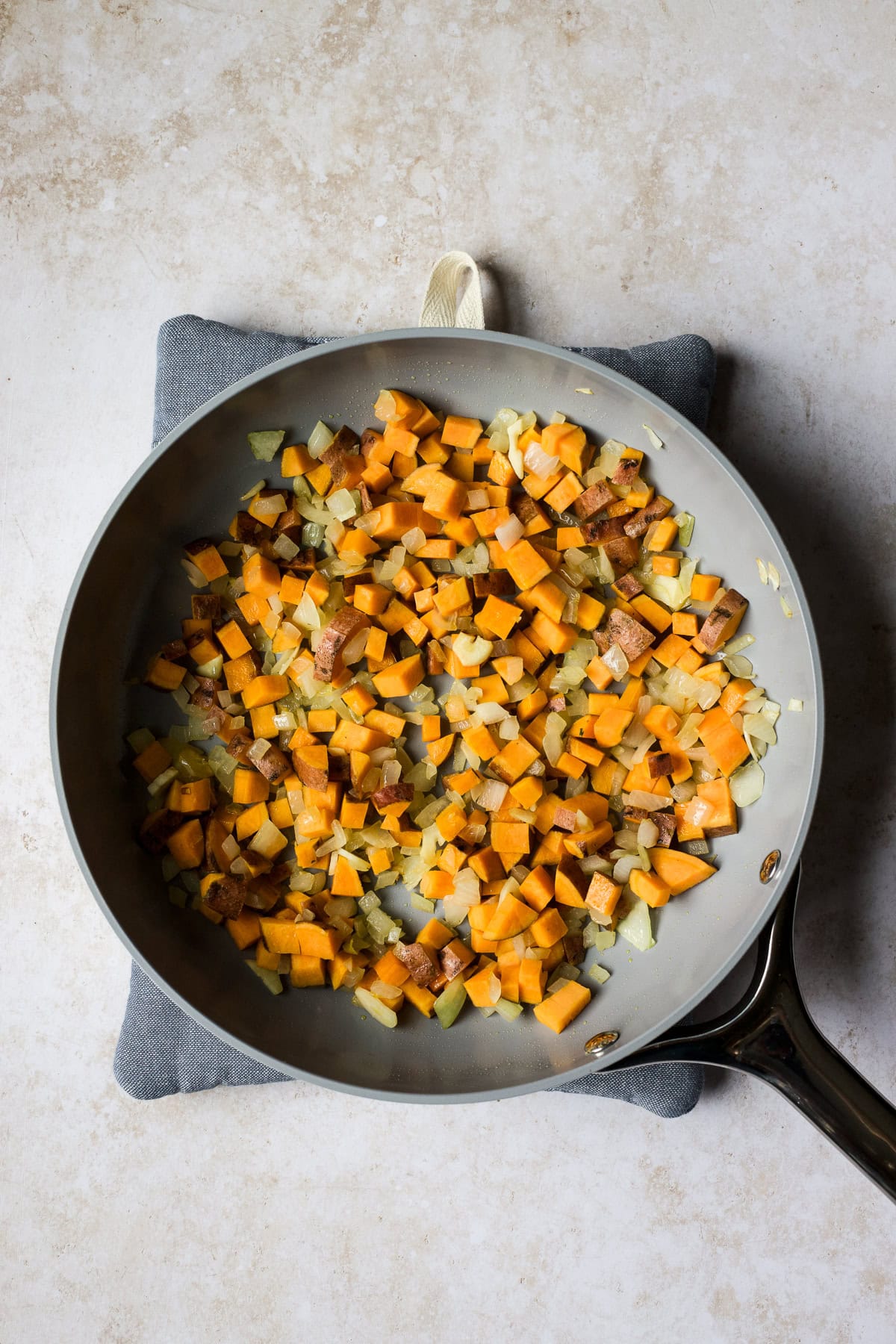 Sautéed onions and sweet potatoes in skillet.