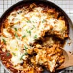 Vegetarian black bean and sweet potato skillet enchiladas being scooped out of pan.