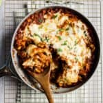 Vegetarian black bean and sweet potato skillet enchiladas being scooped out of pan.