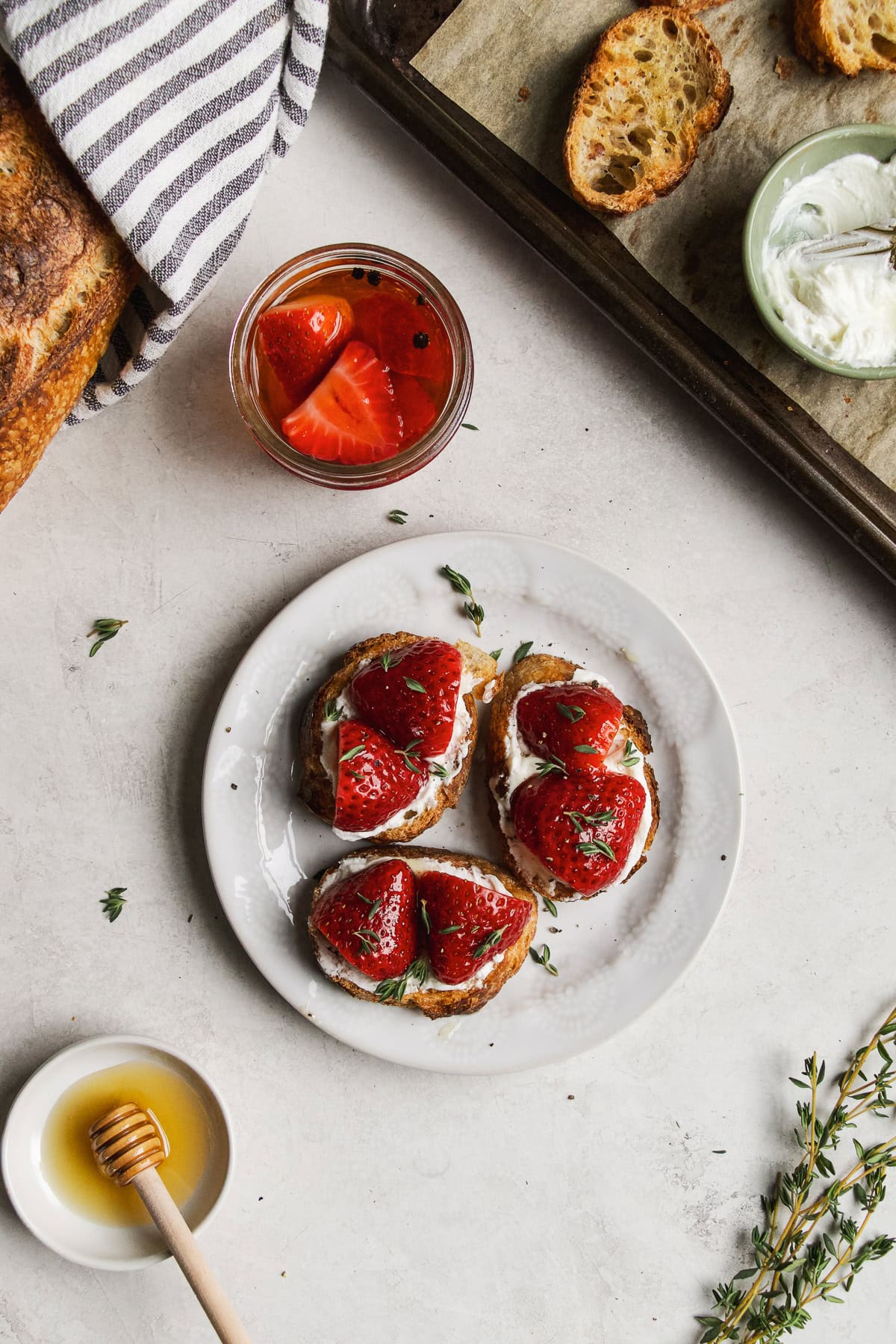 Goat cheese crostini with pickled strawberries on small white plate.