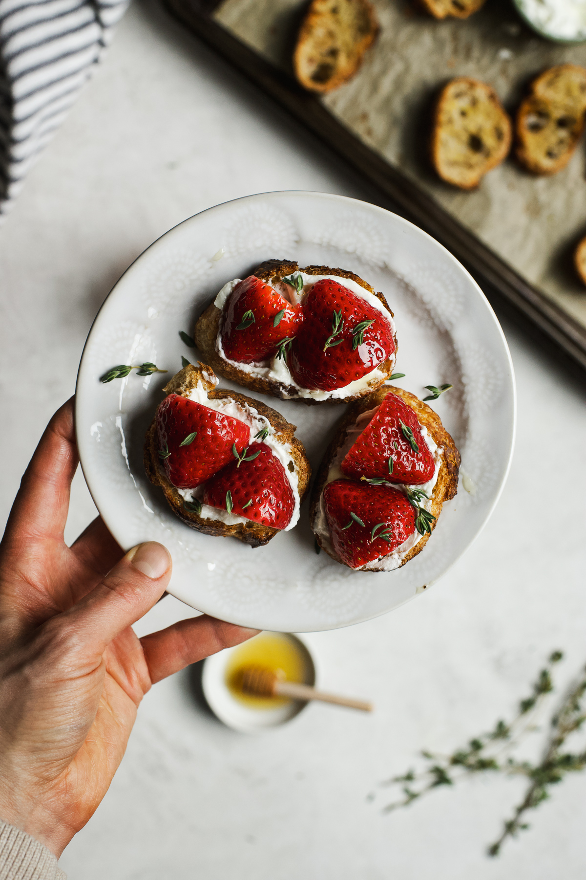 Goat cheese crostini with pickled strawberries on small white plate.