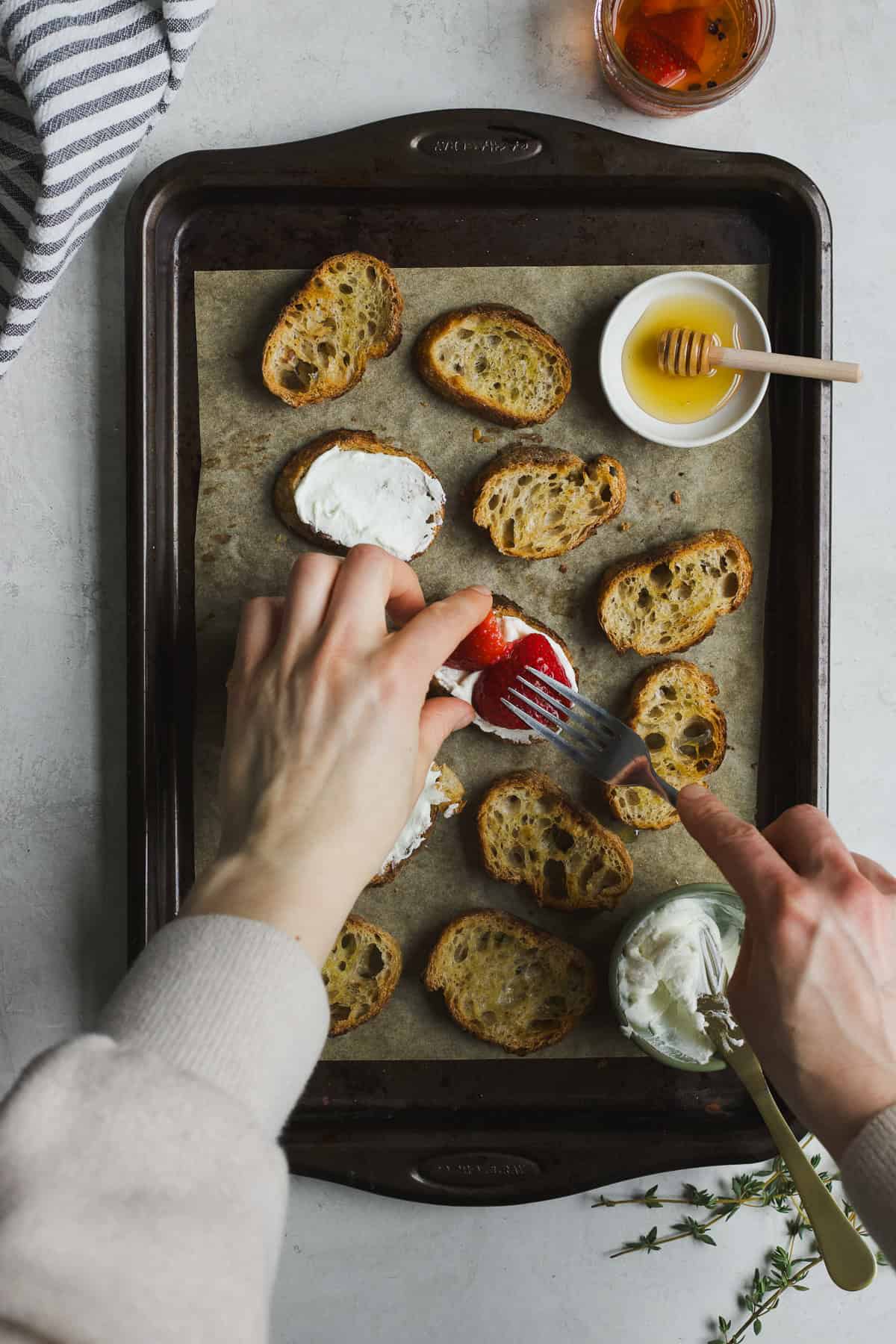 Topping crostini with goat cheese and pickled strawberries.