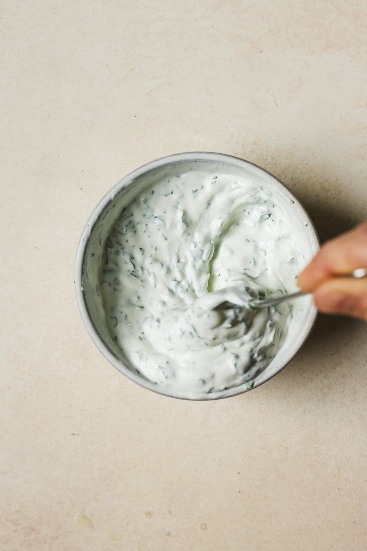 Mixing lemon herb yogurt sauce together in a bowl.
