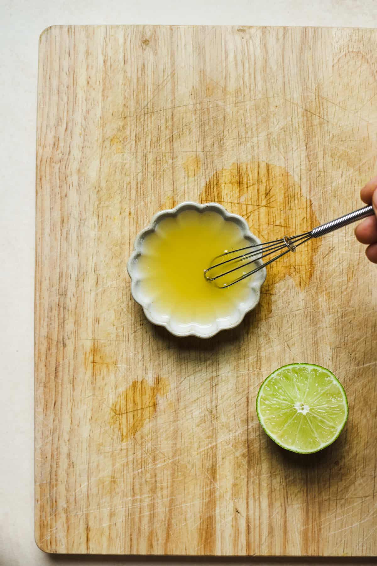 Whisking honey and lime together in a small bowl.