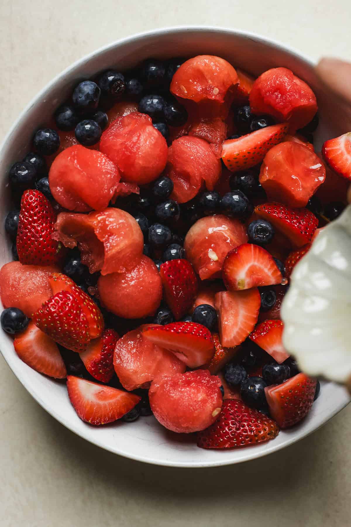 Pouring honey lime dressing over fruit salad.