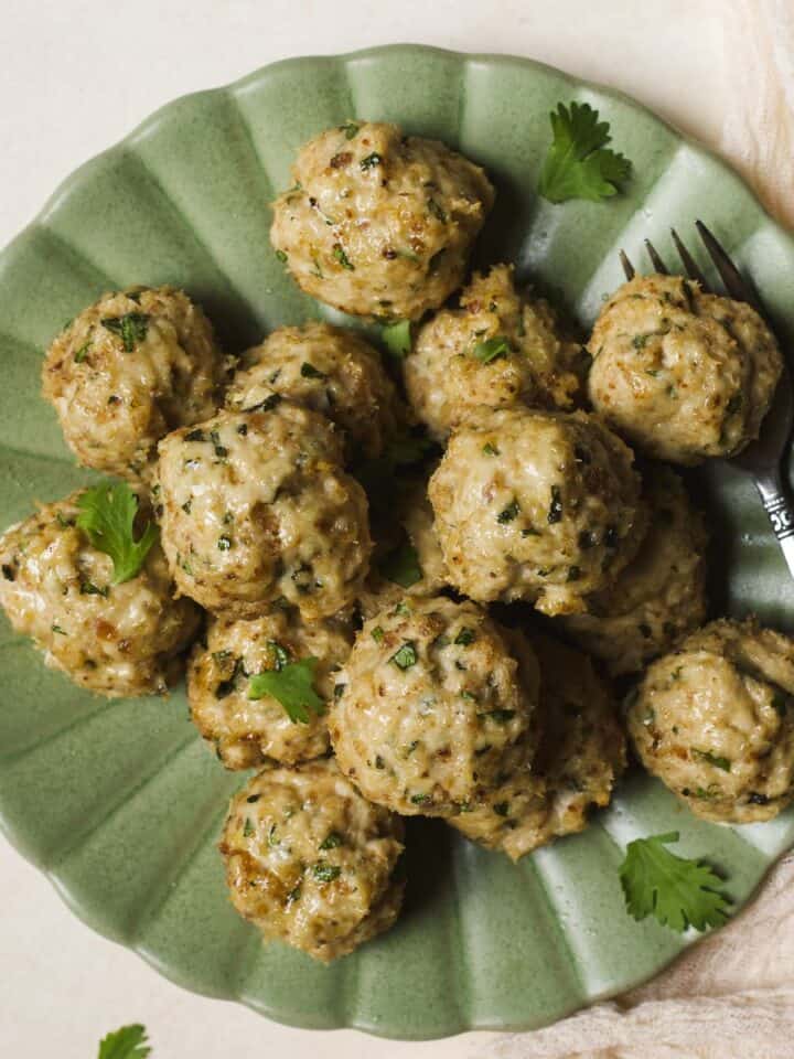 Herby baked chicken meatballs on a plate.