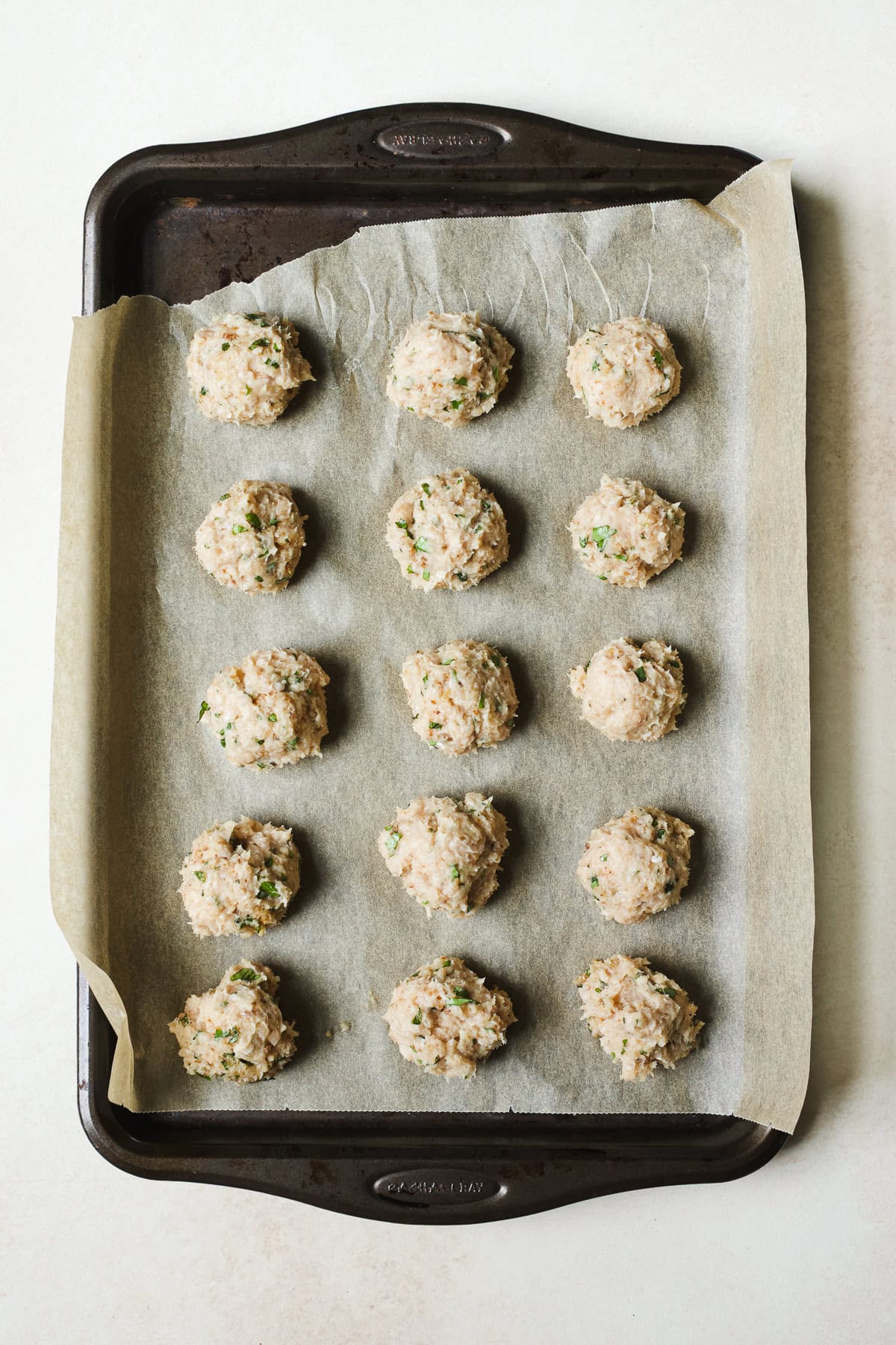 Meatballs on sheet pan before baking.
