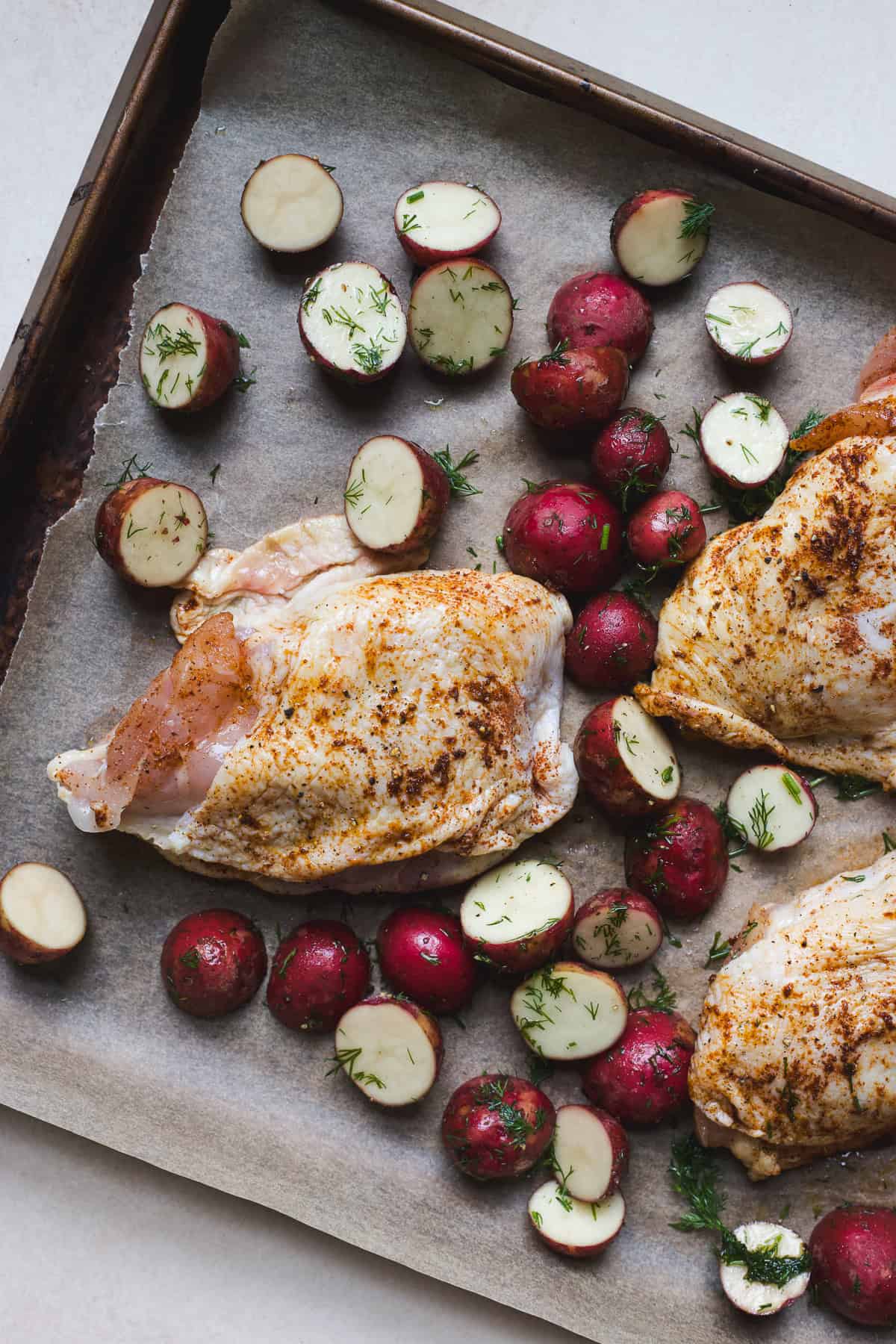 Berbere seasoned chicken thighs and dill potatoes on a sheet pan.