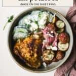 Berbere chicken with dill roasted potatoes in a bowl with creamy cucumber salad and pickled red onions.