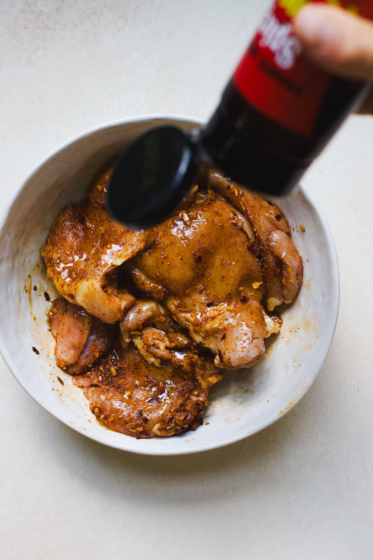 Seasoning chicken thighs with hot honey.