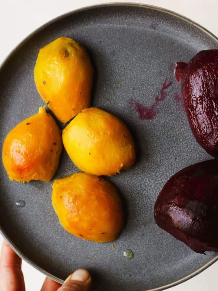 Fully peeled roasted golden beets and roasted red beets on a plate.