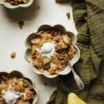 Pear apple crisp in a small bowl, topped with vanilla ice cream.