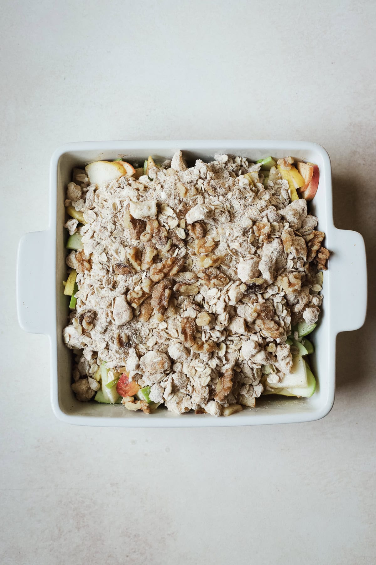 Layering the oat crisp topping over apples and pears in a baking dish.