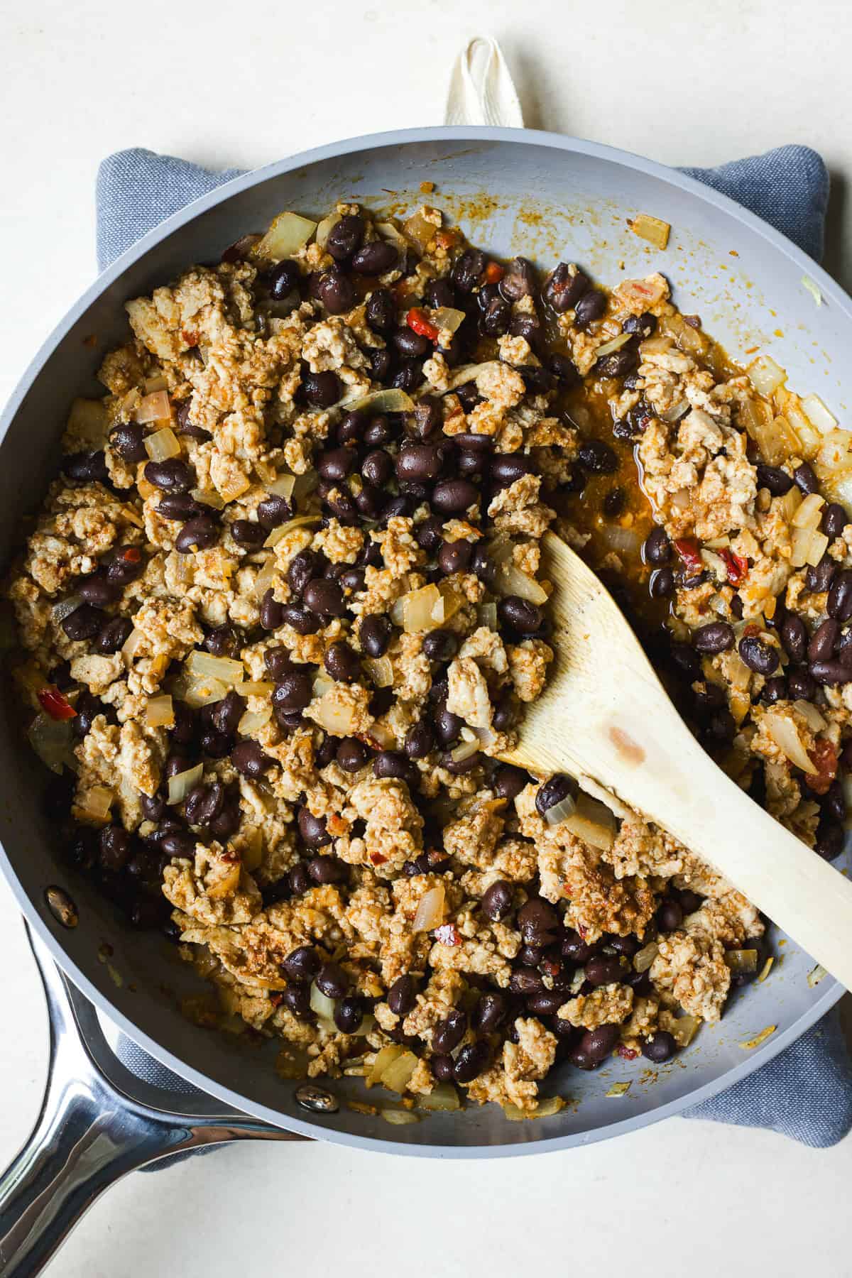 Ground chicken taco meat with black beans in a pan with spoon.