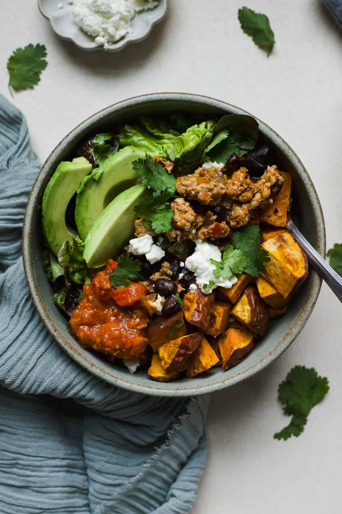 Ground chicken taco sweet potato bowl topped with feta, cilantro, and salsa.