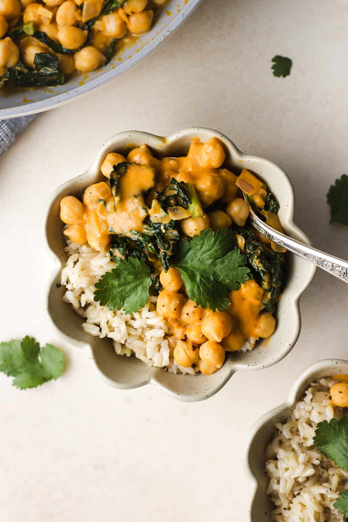 Warm Thai pumpkin curry with chickpeas in a bowl over brown rice.