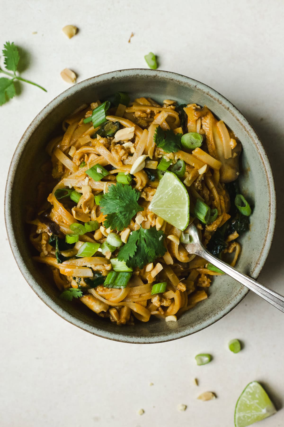 Thai curry noodles with chicken in a bowl with lime and cilantro.