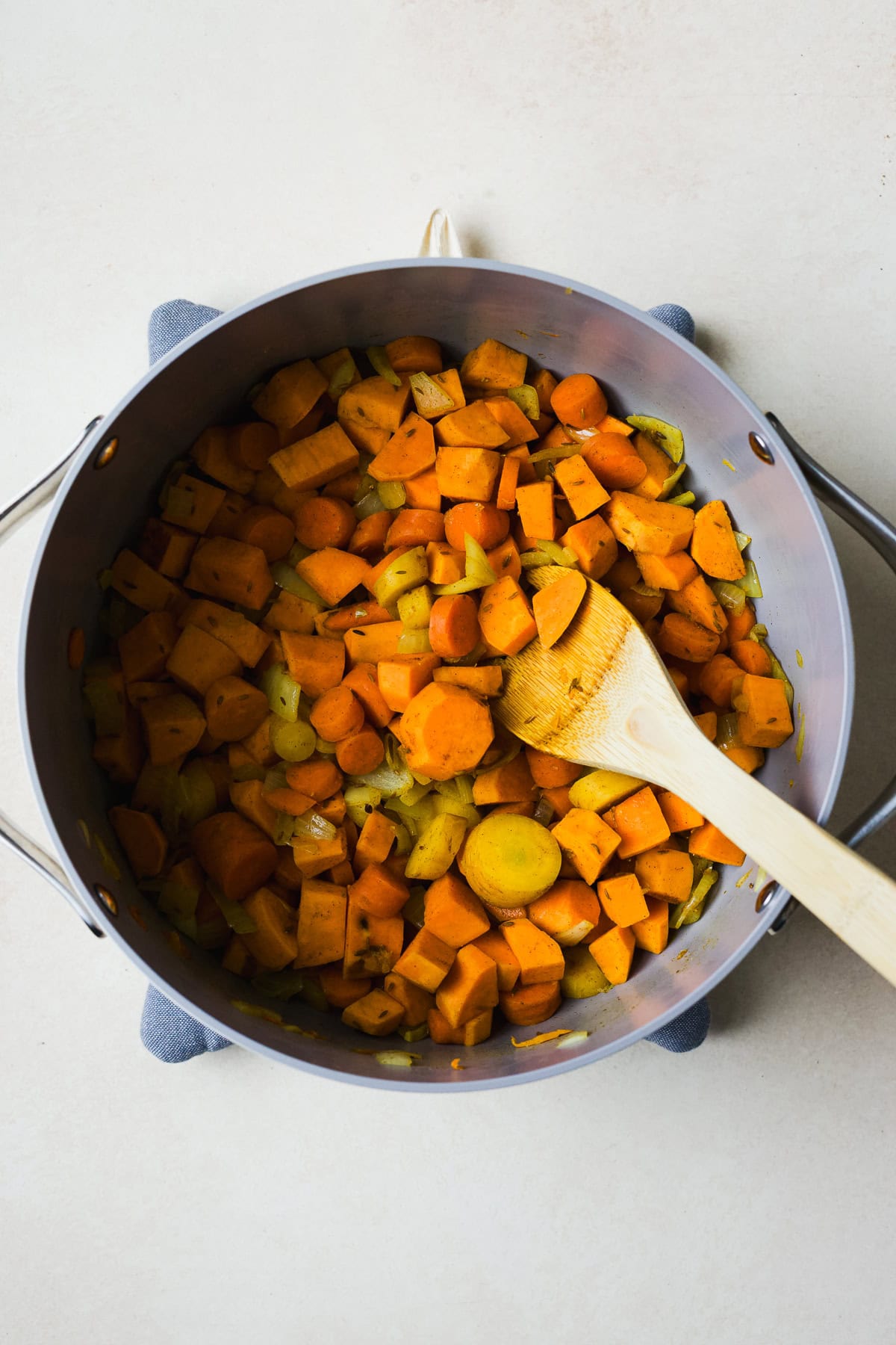 Sautéing carrots, onions, and sweet potato cubes in spices for soup.