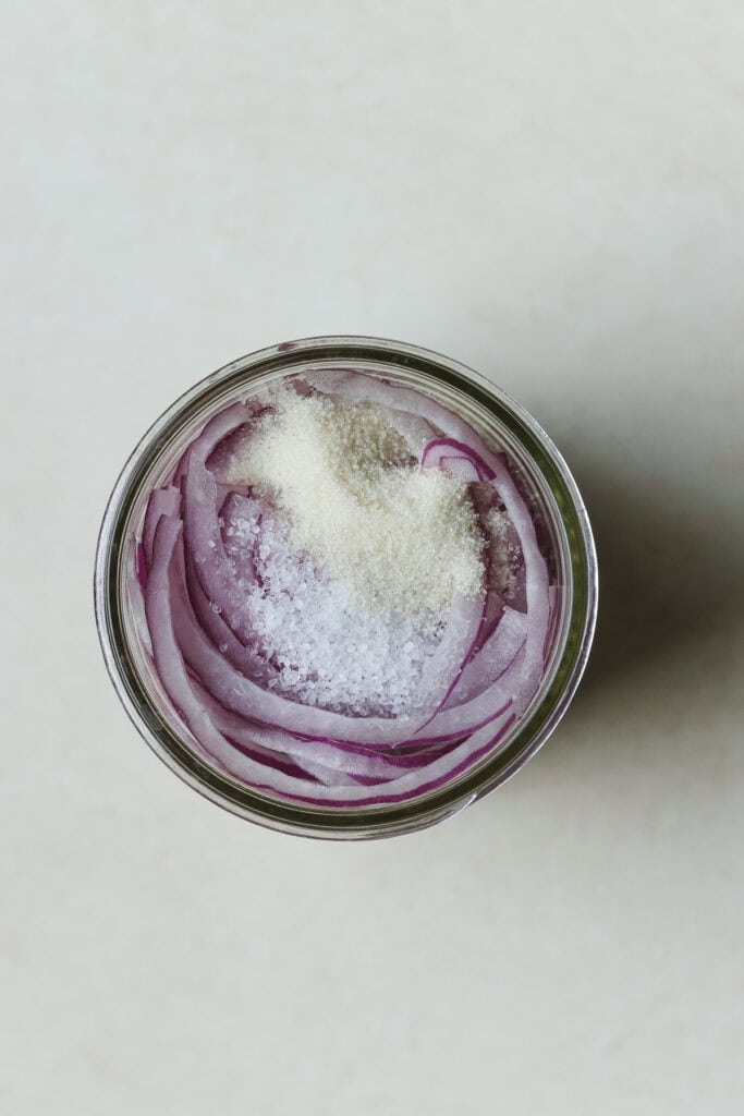 Jar with red onions, salt, and sugar.