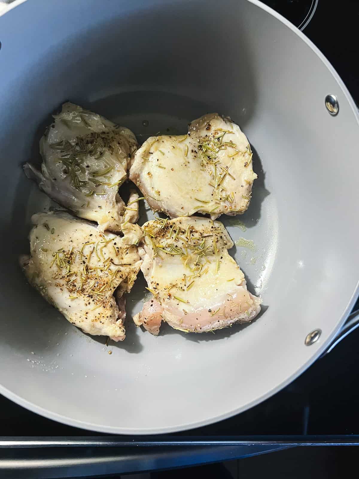 Browning rosemary-seasoned chicken thighs in dutch oven.